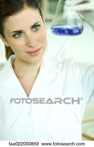 Stock Photo - Female lab worker holding up flask. Fotosearch