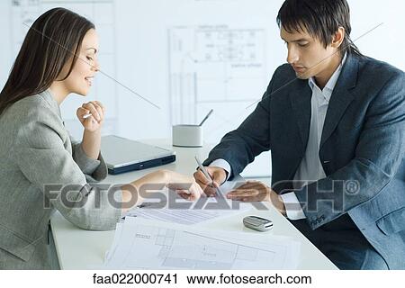 Female real estate agent pointing to document, man signing, blueprints in foreground and background View Large Photo Image Stock Image - Female real estate agent pointing to document, man signing, blueprints in foreground and background. Fotosearch