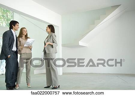 Stock Photo - Female real estate agent showing house to young couple. Fotosearch