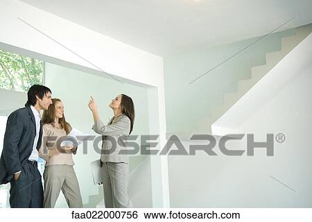 Female real estate agent showing house to young couple, pointing to ceiling View Large Photo Image Stock Photograph - Female real estate agent showing house to young couple, pointing to ceiling. Fotosearch