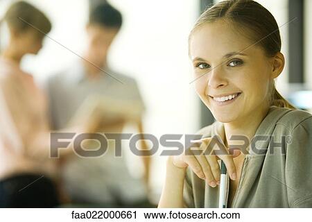 Female student holding pen, smiling at camera, portrait View Large Photo Image Stock Image - Female student holding pen, smiling at camera, portrait. Fotosearch