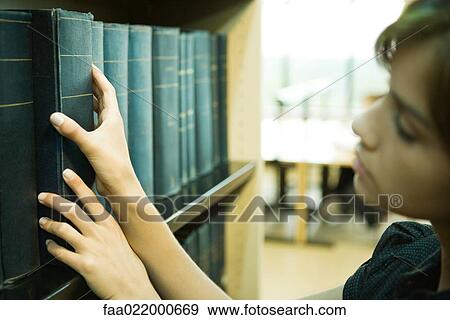 Female student taking reference book from shelf in library View Large Photo Image Stock Photo - Female student taking reference book from shelf in library. Fotosearch