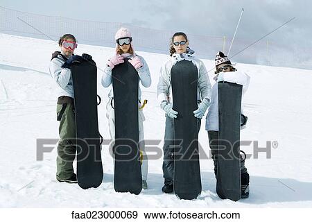 Four young friends standing together, holding snowboards, looking at camera View Large Photo Image Stock Photo - Four young friends standing together, holding snowboards, looking at camera. Fotosearch