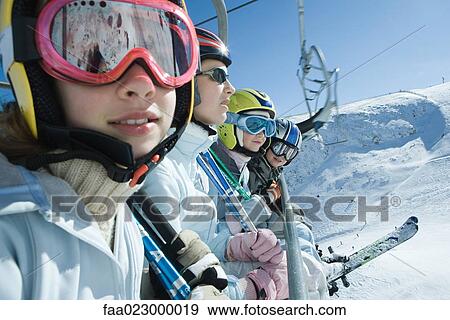 Four young skiers on chair lift, two looking at camera View Large Photo Image Stock Photo - Four young skiers on chair lift, two looking at camera. Fotosearch