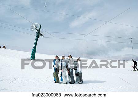 Four young snowboarders standing, lined up, looking up, mid-distance View Large Photo Image Stock Photo - Four young snowboarders standing, lined up, looking up, mid-distance. Fotosearch