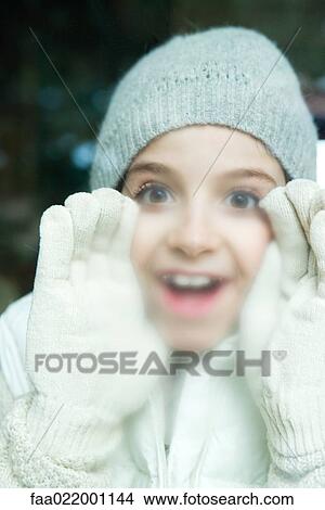 Girl breathing on window, dressed in winter clothing, portrait View Large Photo Image Picture - Girl breathing on window, dressed in winter clothing, portrait. Fotosearch