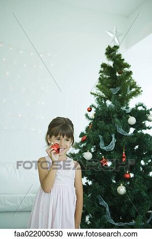 Stock Image - Girl decorating Christmas tree. Fotosearch