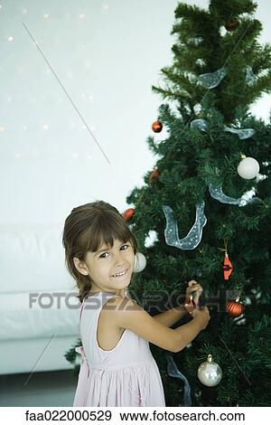 Stock Photo - Girl decorating Christmas tree. Fotosearch