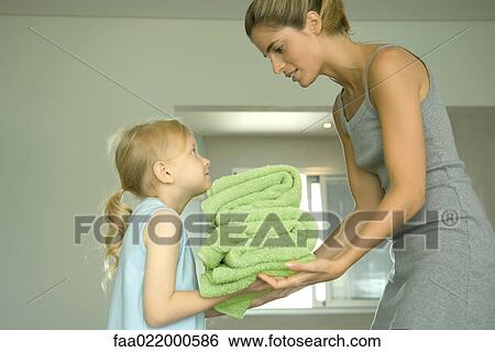 Girl handing mother stack of towels View Large Photo Image Stock Photograph - Girl handing mother stack of towels. Fotosearch
