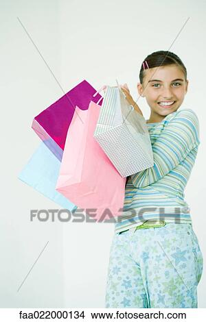 Girl holding up shopping bags View Large Photo Image Picture - Girl holding up shopping bags. Fotosearch