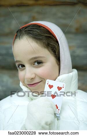 Stock Photo - Girl in winter clothes holding up playing card. Fotosearch