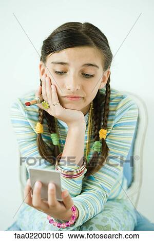 Stock Photography - Girl looking at self in hand mirror, frowning. Fotosearch