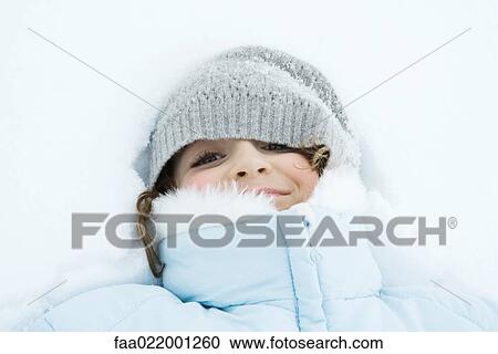 Stock Image - Girl lying in snow, close-up. Fotosearch