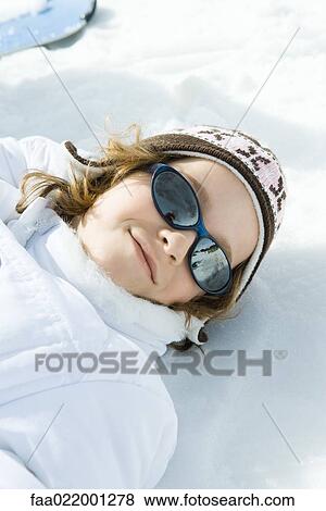 Stock Photo - Girl lying in snow, portrait. Fotosearch