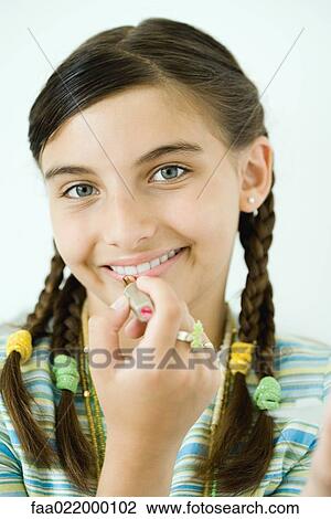 Stock Image - Girl putting on make-up, portrait. Fotosearch