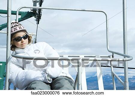 Girl sitting on chair lift, leaning back, looking at camera View Large Photo Image Stock Photograph - Girl sitting on chair lift, leaning back, looking at camera. Fotosearch