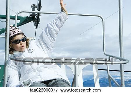 Girl sitting on chair lift, waving, looking away View Large Photo Image Stock Photo - Girl sitting on chair lift, waving, looking away. Fotosearch