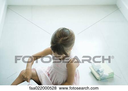 Stock Photo - Girl sitting on floor, opening presents. Fotosearch