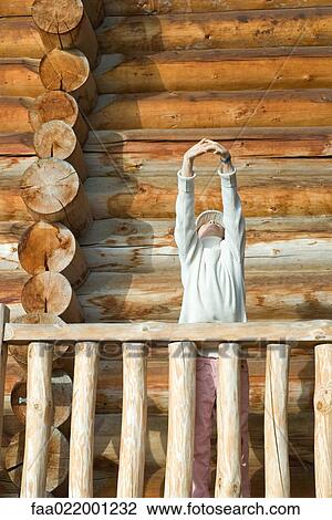 Girl standing on deck of wood cabin, stretching arms over head View Large Photo Image Stock Image - Girl standing on deck of wood cabin, stretching arms over head. Fotosearch