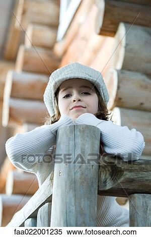 Stock Photography - Girl standing on deck of wood cabin, leaning on rail. Fotosearch
