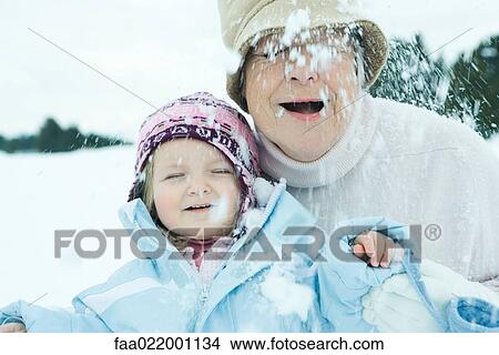 Picture - Grandmother and granddaughter in snow, both smiling, eyes closed. Fotosearch