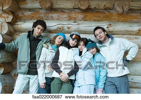 Stock Photo - Group in winter clothes standing together, leaning against log wall, three quarter length, portrait. Fotosearch
