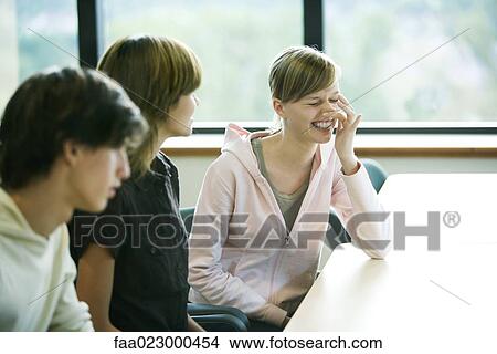 Group of college students sitting at table, one young woman wiping nose View Large Photo Image Picture - Group of college students sitting at table, one young woman wiping nose. Fotosearch