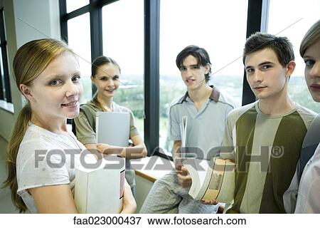 Group of college students standing around, holding books and binders, smiling at camera View Large Photo Image Stock Photo - Group of college students standing around, holding books and binders, smiling at camera. Fotosearch
