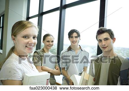 Group of college students standing around, holding books and binders, smiling at camera View Large Photo Image Stock Photo - Group of college students standing around, holding books and binders, smiling at camera. Fotosearch