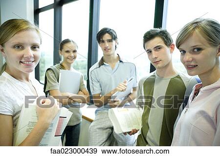 Group of college students standing around, holding books and binders, smiling at camera View Large Photo Image Stock Photo - Group of college students standing around, holding books and binders, smiling at camera. Fotosearch