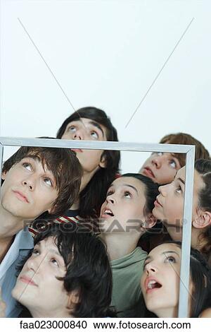 Group of young friends holding up picture frame, looking up, portrait View Large Photo Image Stock Image - Group of young friends holding up picture frame, looking up, portrait. Fotosearch