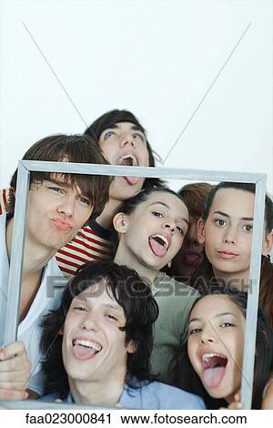 Group of young friends holding up picture frame, making faces at camera, portrait View Large Photo Image Stock Image - Group of young friends holding up picture frame, making faces at camera, portrait. Fotosearch