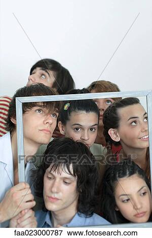 Stock Photo - Group of young friends holding up picture frame, looking in different directions, portrait. Fotosearch