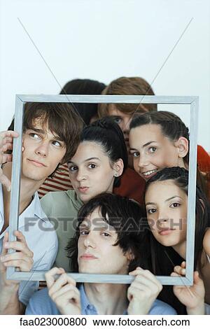 Group of young friends posing for photo, holding up picture frame, looking at camera, portrait View Large Photo Image Stock Image - Group of young friends posing for photo, holding up picture frame, looking at camera, portrait. Fotosearch