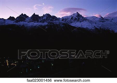 Illuminated town at bottom of snow-covered mountains View Large Photo Image Stock Photograph - Illuminated town at bottom of snow-covered mountains. Fotosearch
