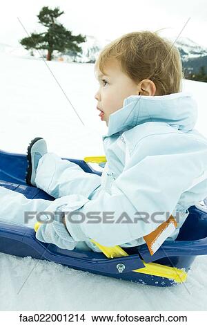 Little boy sitting on sled, looking up, side view View Large Photo Image Picture - Little boy sitting on sled, looking up, side view. Fotosearch