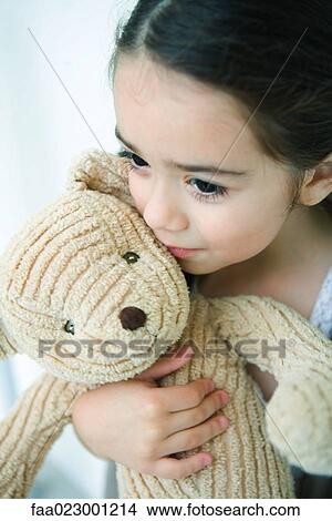 Picture - Little girl holding teddy bear, looking away, portrait. Fotosearch