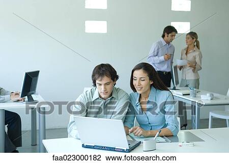 Male and female colleagues working at laptop together View Large Photo Image Stock Image - Male and female colleagues working at laptop together. Fotosearch