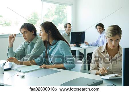 Stock Photography - Male and female colleagues working in office. Fotosearch