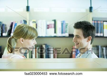 Male and female college students face to face in library, smiling at each other View Large Photo Image Stock Image - Male and female college students face to face in library, smiling at each other. Fotosearch
