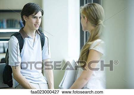 Male and female college students standing face to face in college library View Large Photo Image Stock Photo - Male and female college students standing face to face in college library. Fotosearch