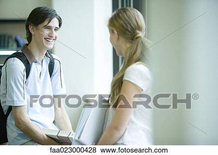Male and female college students standing face to face in college library, laughing View Large Photo Image Stock Photo - Male and female college students standing face to face in college library, laughing. Fotosearch