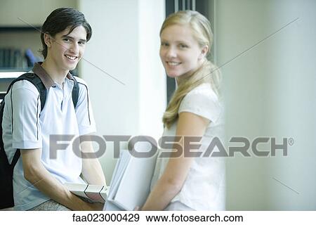Male and female college students standing in college library, smiling at camera View Large Photo Image Stock Photo - Male and female college students standing in college library, smiling at camera. Fotosearch