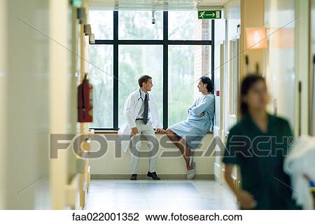 Male doctor and patient sitting by window in hospital corridor, discussing, focus on background View Large Photo Image Stock Image - Male doctor and patient sitting by window in hospital corridor, discussing, focus on background. Fotosearch
