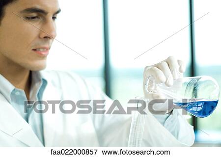 Stock Photo - Male lab worker transferring solution from flask to graduated cylinder. Fotosearch