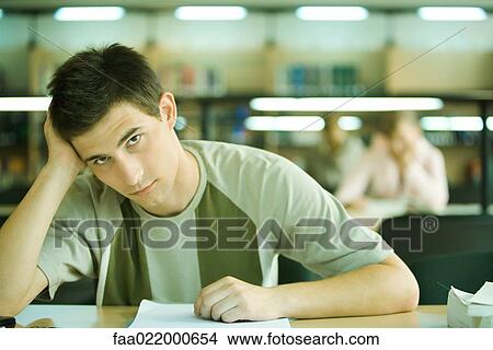 Male student studying in library, looking at camera View Large Photo Image Picture - Male student studying in library, looking at camera. Fotosearch
