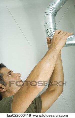 Man adjusting air duct View Large Photo Image Stock Photo - Man adjusting air duct. Fotosearch