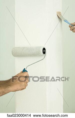 Picture - Man and woman painting with paintbrush and roller, close-up of hands. Fotosearch