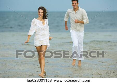 Man and young female companion on beach, hurrying toward camera, smiling, man in background, full length View Large Photo Image Stock Photo - Man and young female companion on beach, hurrying toward camera, smiling, man in background, full length. Fotosearch