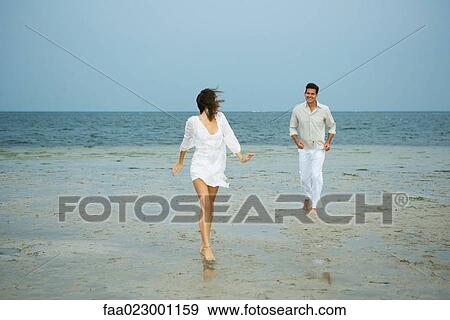 Man and young female companion on beach, walking toward camera, man in background, full length View Large Photo Image Stock Photo - Man and young female companion on beach, walking toward camera, man in background, full length. Fotosearch
